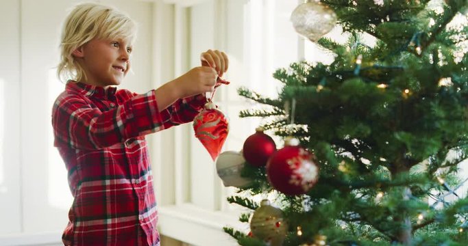 Cute young boy hanging ornaments on christmas tree