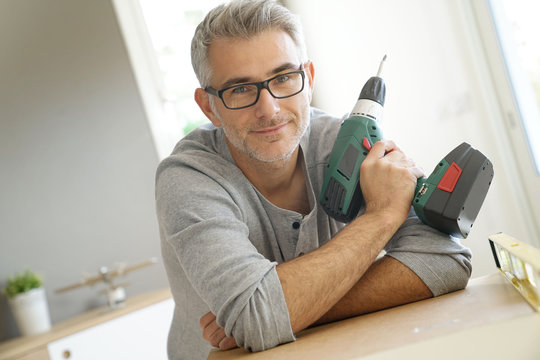 Portrait of cheerful man with electric drill