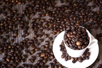Coffee concept: fried coffee beans in porcelain white coffee cup