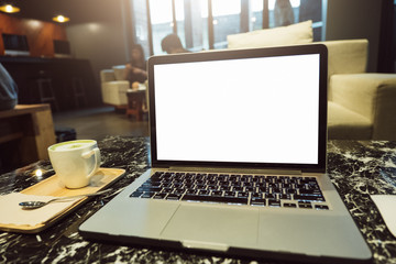Front view of cup and laptop on table in office and background in the coffee shop
