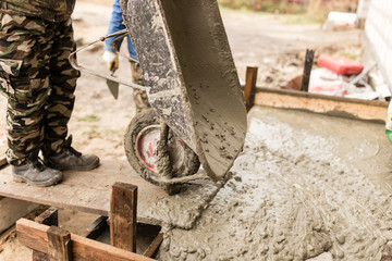 worker pours concrete mortar on a construction site