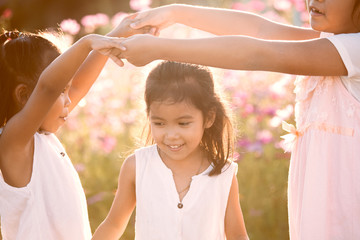 Obraz premium Children having fun to play together in the cosmos flower field in summer time with sunlight