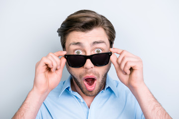 Close up portrait of attractive guy with wide opened eyes and mouth, holding eyelets of black...