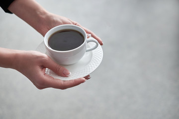 Close-up of a woman's hand holding a cup of hot coffee in office