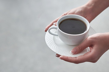 Close-up of a woman's hand holding a cup of hot coffee in office