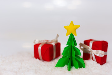 miniature paper pine tree figure with felted star on the top and red gift boxes, selective focus
