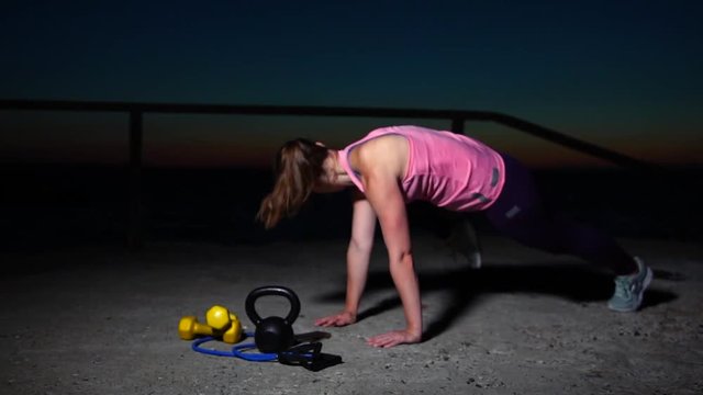 Young Sportswoman Practicing Interval Training on the Beach. Fitness Female Doing Mountain Climber Exercise Using Smartphone Application for Workout. Static Shot