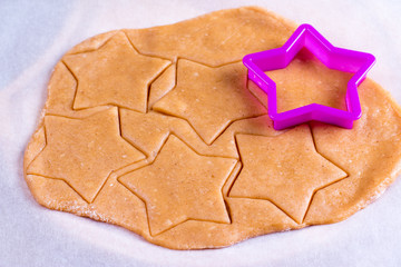 Gingerbread cookies in the making on wooden cutting board pastry raw dough star shape cutters