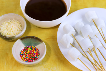 marshmallows on a sticks, laying on a white plate. prepared for fondue.