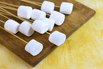 Fototapeta na wymiar marshmallows on a sticks, laying on a chopping board. prepared for fondue.
