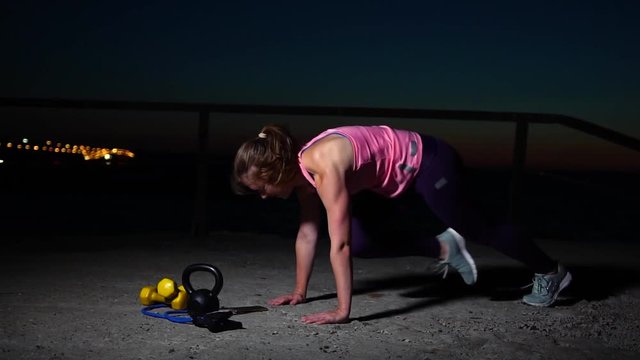 Sportswoman Doing Mountain Climber Exercise. Fitness Female Working Out on the Beach at Sunset. Athletic Young Woman is Engaged in Outdoor Sports.