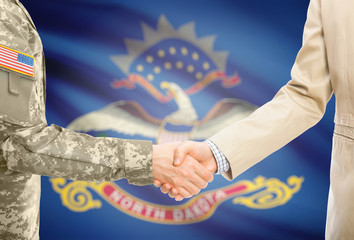 USA military man in uniform and civil man in suit shaking hands with certain USA state flag on background - North Dakota