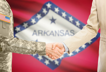 USA military man in uniform and civil man in suit shaking hands with certain USA state flag on background - Arkansas