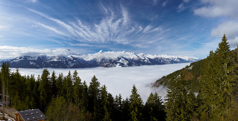 Panoramic view of foggy valley and Alps mountains with blue sky and white fleecy clouds