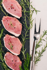 Raw meat. Beef steak with rosemary and spices on a white wooden background. Top view. Free space for text.