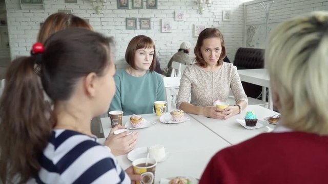 A female team sits in a cafe for a cup of tea. Colleagues communicate on different topics during lunch. The girls met in a cafe to eat a cake.