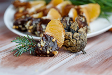 Mandarin in chocolate glaze and nuts on the table