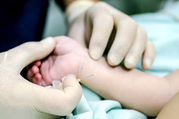 An anesthesiologist holds a needle from the catheter in his hand. The doctor gropes a vein for setting up a peripheral caterer before the operation.