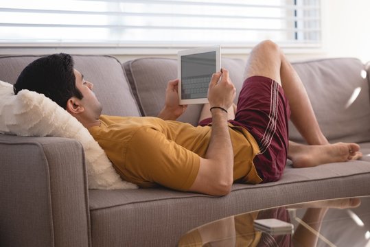 Man using digital tablet on sofa in living room
