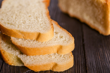 White bread sliced on a dark wooden table. Selctive focus. Blurred background.