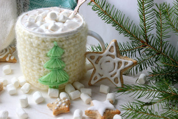 Obraz na płótnie Canvas Christmas composition. Hot cocoa with marshmallows in knitted Cup, scattered ginger cookies in glaze on a white background
