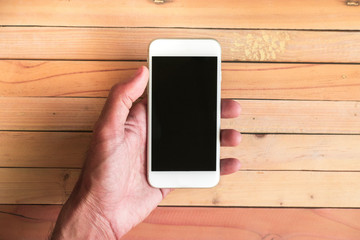 Holding smartphone on wood background.using wallpaper for education, business photo.Take note of the product for mobile concept, object or copy space.