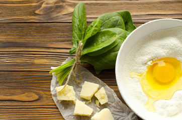 Dough, spinach,parmesan on wooden background are ready for cooking pasta