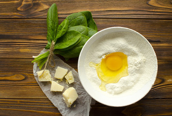 Dough, spinach,parmesan on wooden background are ready for cooking pasta