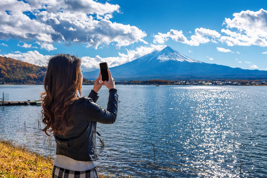 Woman use mobile phone take a photo at Fuji mountains, Kawaguchiko lake in Japan.