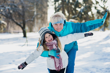 Active grandmother and little girl play in snow in winter sunny day