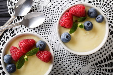 vanilla pudding decorated with raspberries and blueberries close-up. Horizontal top view
