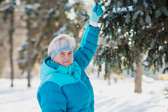 Mature active blonde woman in blue sporty jacket in winter park