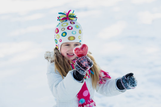 Little girl shows heart outdoor in winter. Save warmth