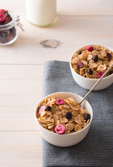 Bowl of homemade muesli with nuts, berries, dried fruits, milk on white wooden background. Healthy breakfast. 
