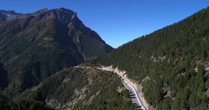 Mountain road, Cinema 4k aerial view over a alpine road and a alp, revealing a mountain town, on a sunny fall day, on simplon pass, in wallis, of the alps in Switzerland