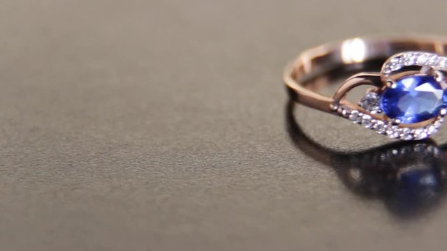 Beautiful engagement female gold ring with precious stones on a black background