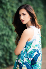 Sunny positive portrait of sexy stunning girl in short colorful dress having fun on the street