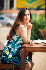 Sunny positive portrait of sexy stunning girl in short colorful dress having fun on the street