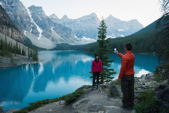 Man taking picture of woman with mobile phone