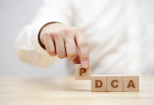 Hand and word PDCA (Plan, Do, Check, Act) made with wooden building blocks