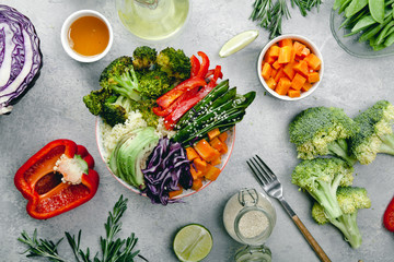 Tasty healthy bowl for lunch with couscous, baked broccoli and carrots cut in cubes, fried peas, avocados and red cabbage. Easy vegetarian diet concept. Rustic background. Top view.