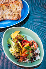 Grilled shrimp salad with mango, tomato, balsamic and pita bread on colorful plates