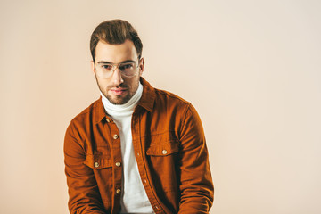 Fototapeta premium portrait of handsome young man looking at camera isolated on beige