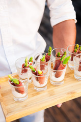 Canape from asparagus and dried ham with creamy sauce in glass on wooden tray