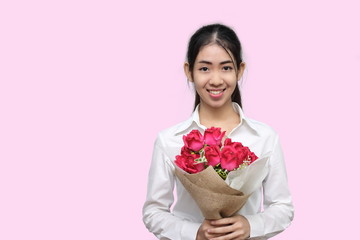 Portrait of attractive young Asian woman holding a bouquet of red roses on pink isolated background. Valentine's day concept.