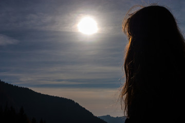 Fototapeta premium Girl looking at the sun.Valley and mountains in the background