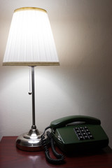 Hotel lamp and a telephone on reddish furniture.