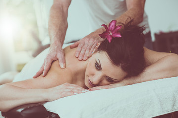 Obraz na płótnie Canvas Beautiful young woman getting massage, light effect