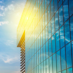 Office building on a light cloudy day.Blue sky in the background.Worm sun reflected.Right angle