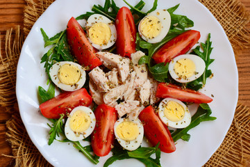 Chicken breast, tomatoes, quail eggs and arugula salad. Healthy and tasty salad for lunch or dinner. Top view